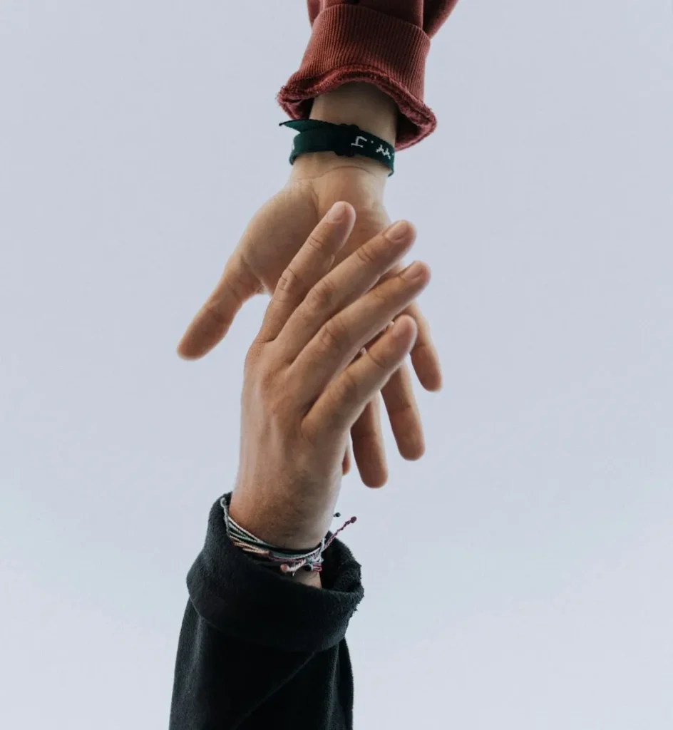 One hand reaches to another for assistance