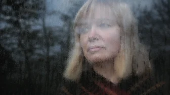 Melancholy woman looks through a window on a rainy day